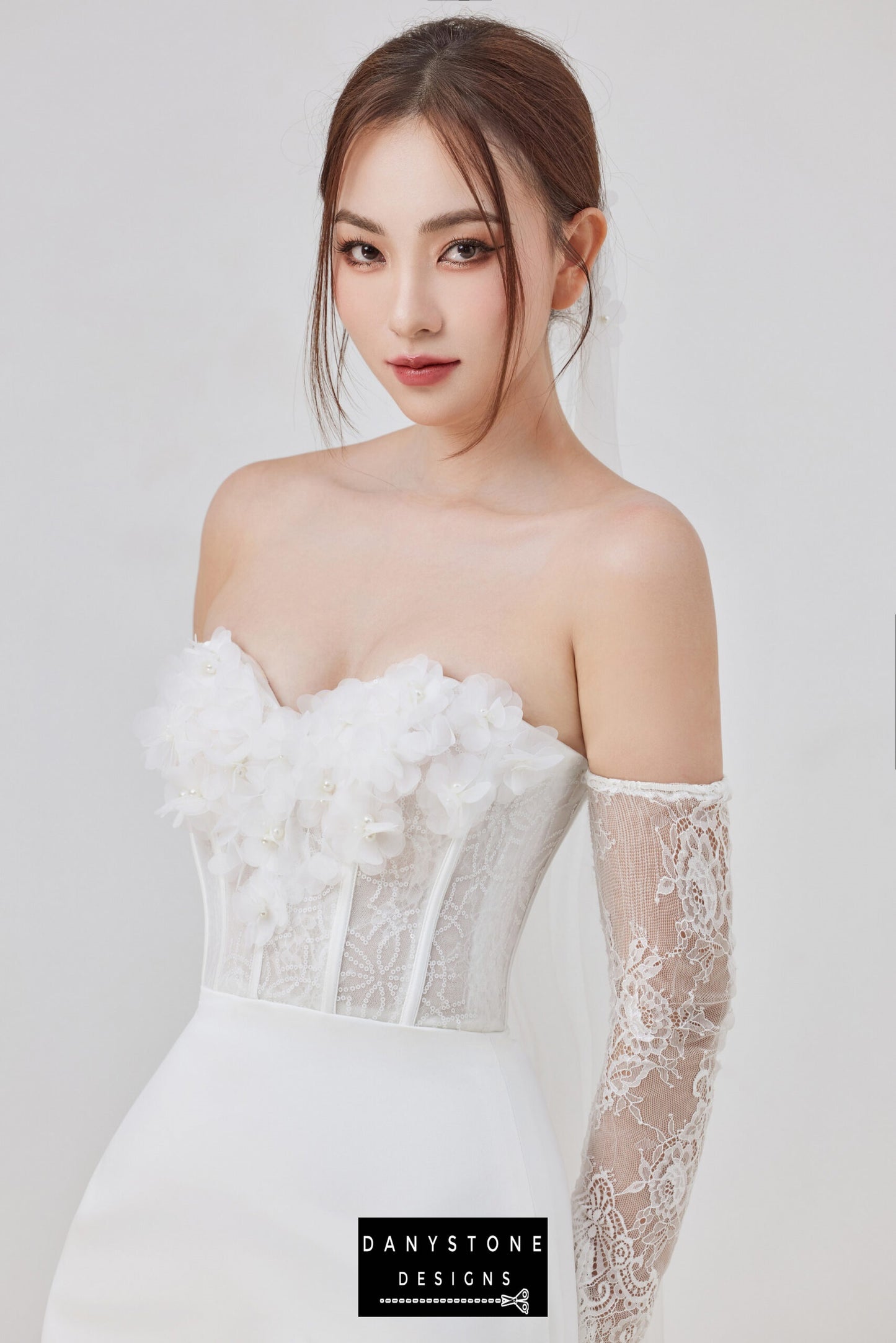 Side view of the model wearing a strapless wedding dress with 3D flowers and lace sleeves.