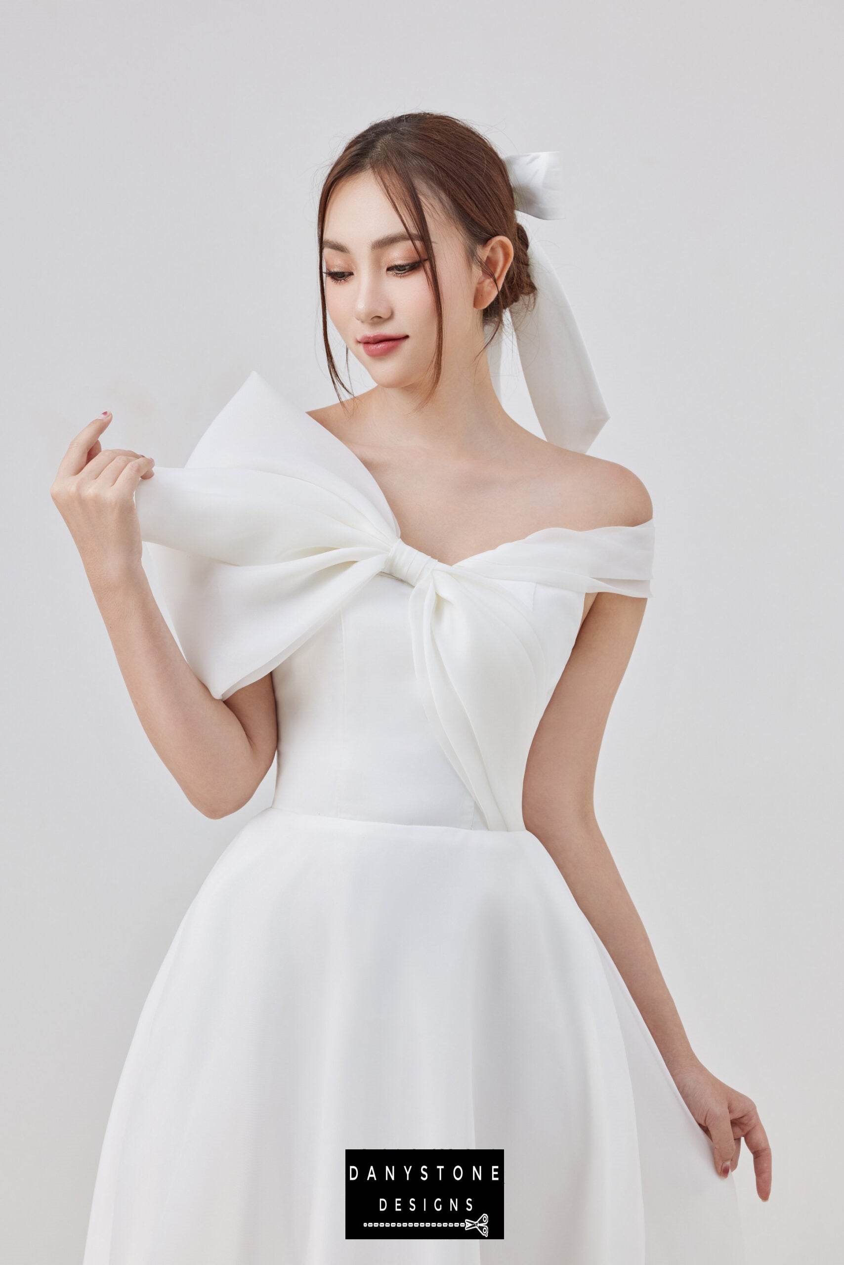 Elegant off-shoulder wedding dress with large bow detail and flowing skirt