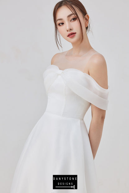 Elegant bride in the Angel Whisper Chiffon Dress by Danystone Designs, showcasing off-the-shoulder neckline and bow detail.