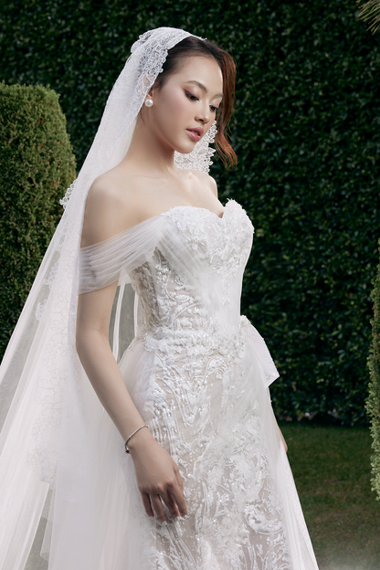 Woman in a white wedding dress with a veil standing outdoors.