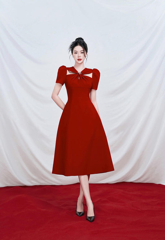 Woman wearing a red dress standing on a red carpet with a white draped curtain background