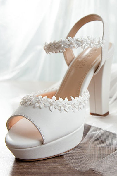 Close-up of hand-woven flowers on matte leather platform heels, highlighting intricate craftsmanship.